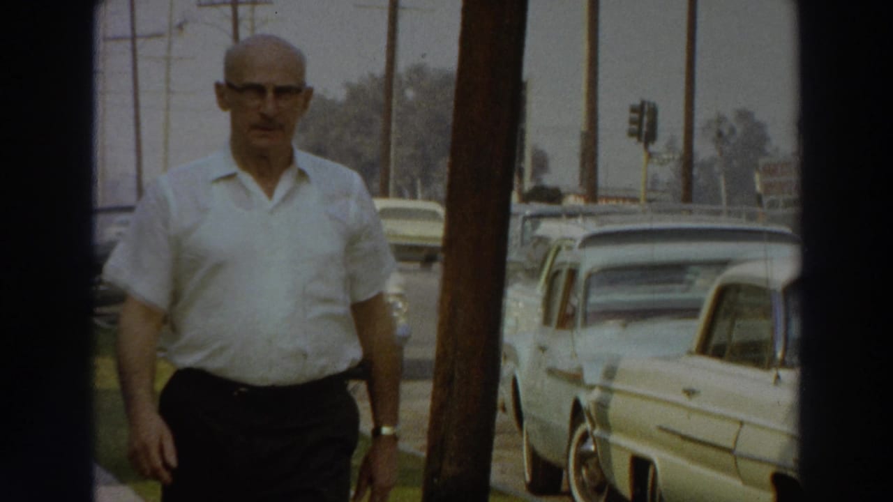 1966 Puerto Rico street view with a man walking on the sidewalk past parked cars, utility poles, and traffic signals.