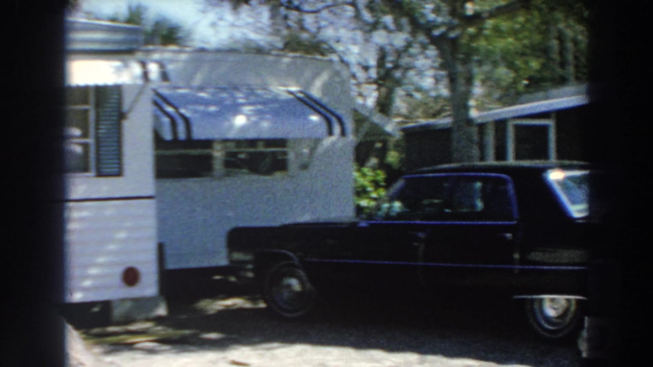 1966 Puerto Rico 8mm frame showing a white mobile home with striped awnings and a black sedan in a sunny residential area.