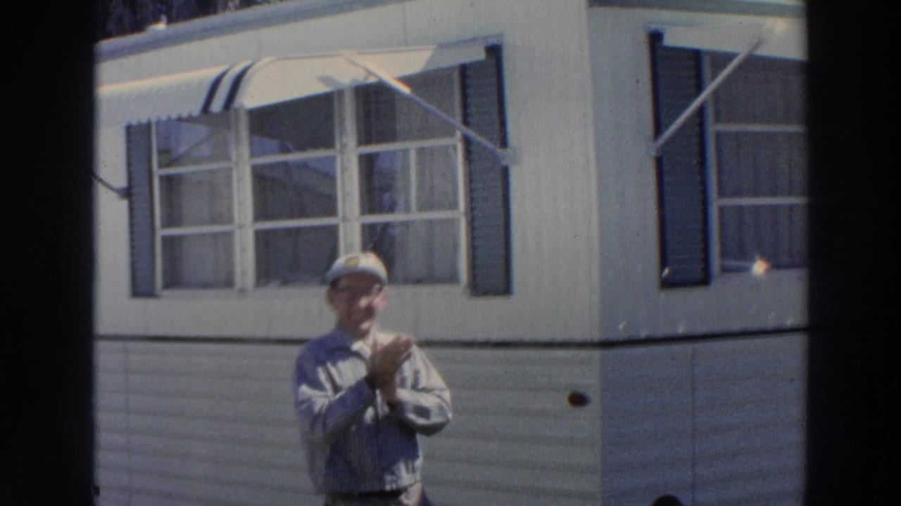 In Puerto Rico, 1966, a man in glasses and a white cap stands with hands together below a window and striped awning.