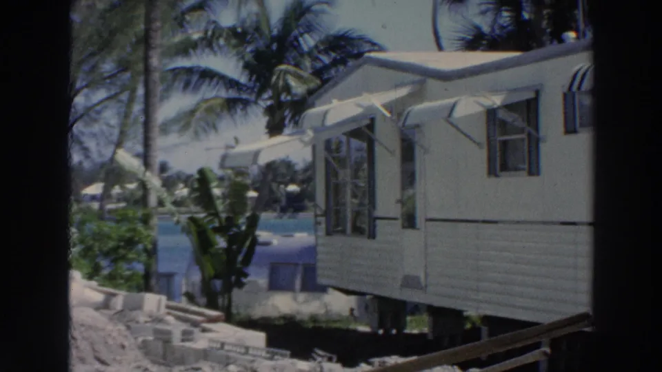 The 1966 Puerto Rico clip ends on a side angle of the white mobile home, with striped awnings, open windows, palms, and water in view.