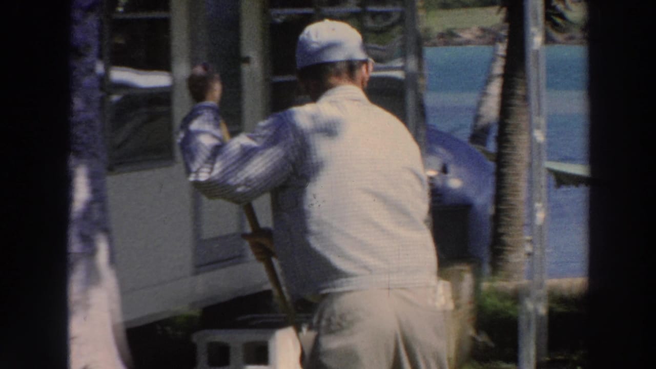 Man in cap seen from behind mopping beside a building exterior.