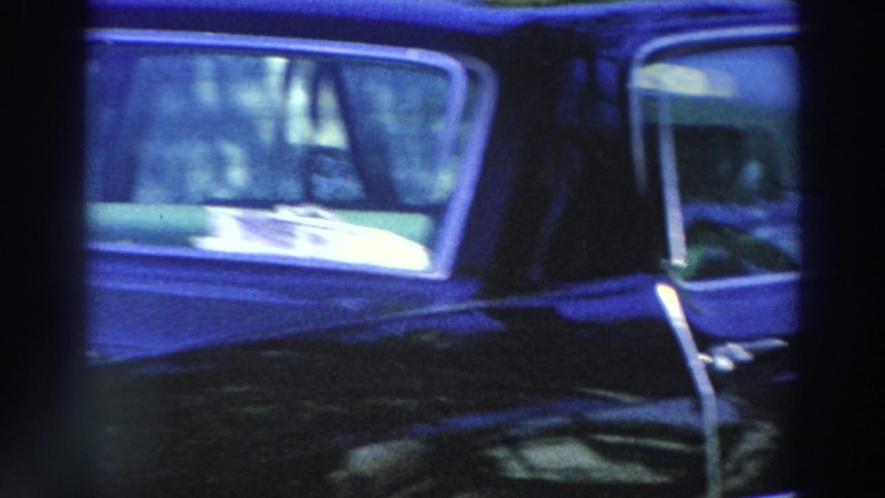 Dark sedan parked near a house, partially framed by film gate edges.