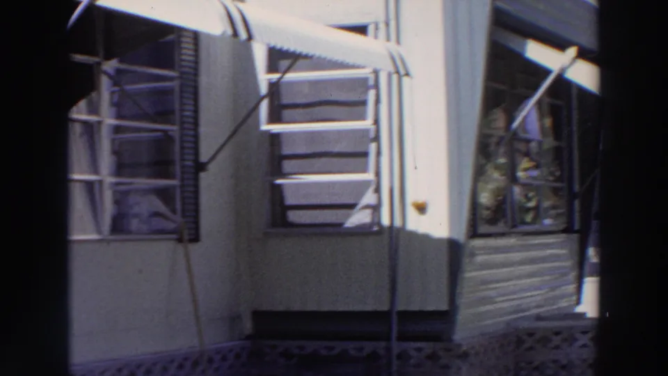 1966 Puerto Rico home exterior with louvered windows, angled awnings, horizontal siding, and patterned concrete blocks below.