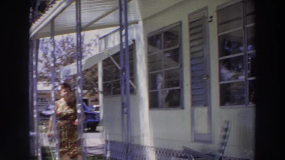1966 Puerto Rico frame showing the woman moving near the porch edge beside a light house and background car.