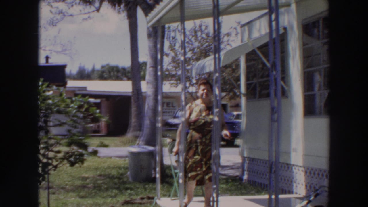 Woman walking past porch posts outside a light mobile home.