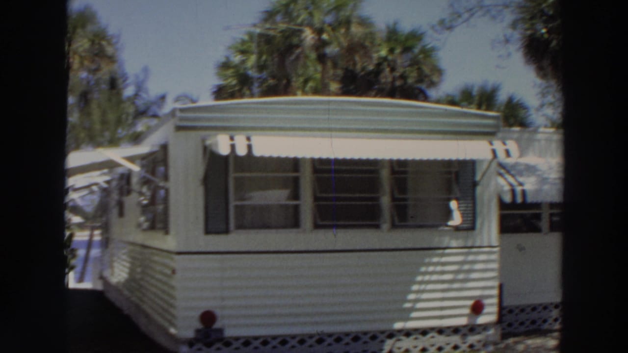 1966 Puerto Rico 8mm frame showing a closer view of a white mobile home with windows, awnings, and lawn.