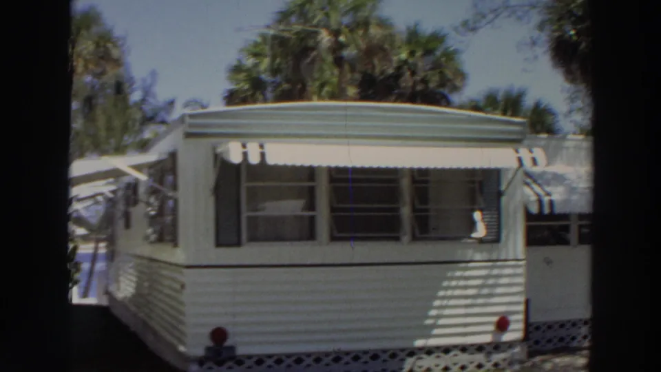 1966 Puerto Rico 8mm frame showing a closer view of a white mobile home with windows, awnings, and lawn.