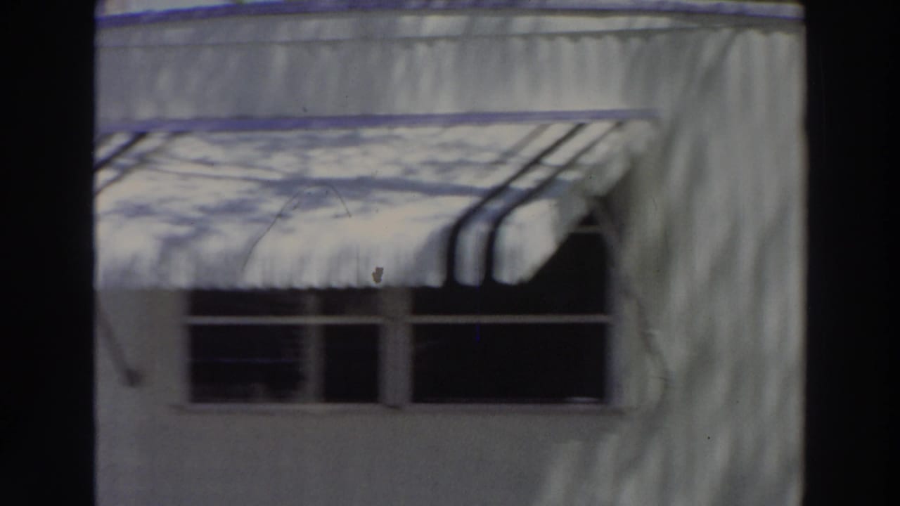 1966 Puerto Rico frame of a light-colored building exterior with a striped awning, dark windows, and shadows across the wall.