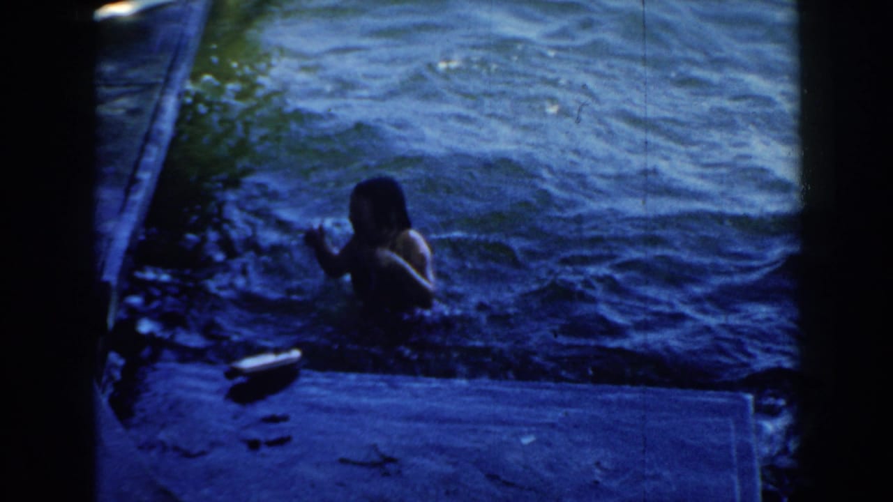 Woman swimming near a dock in blue lake water.