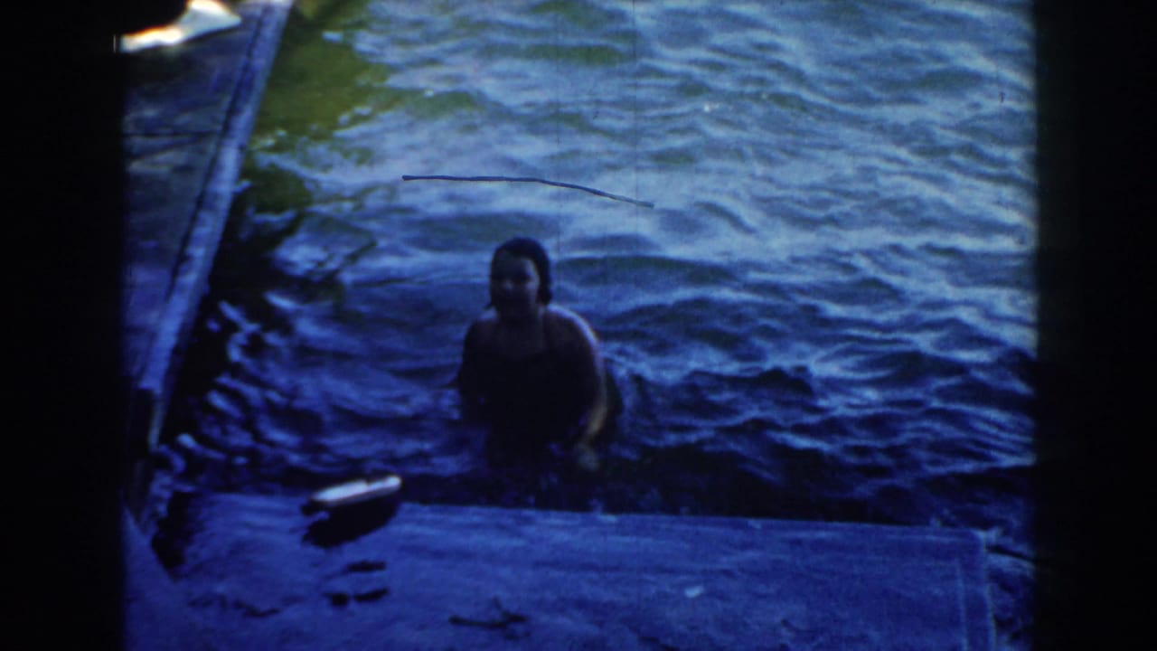 Woman faces the camera while swimming near a dock.