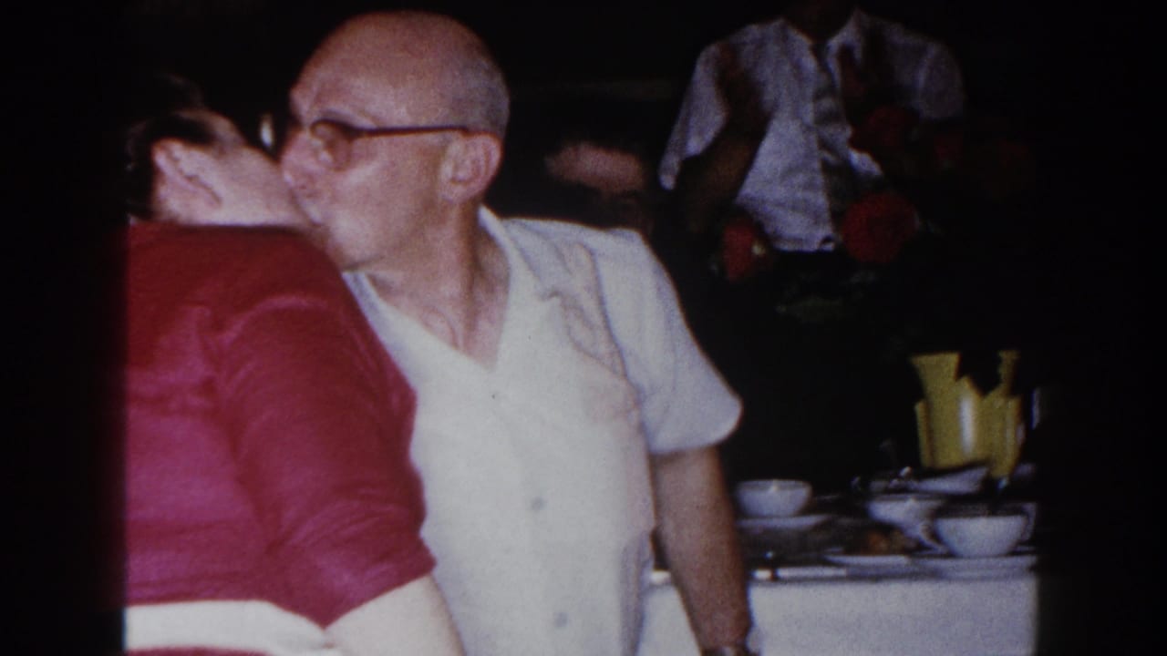 In 1960 Brighton, Michigan home-movie footage, an older man in glasses kisses a woman in a red dress at a family dinner table.