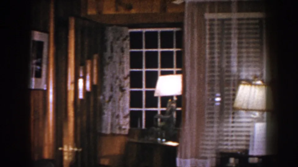 A Brighton home interior shows wood paneling, a multi-pane window with curtains, a lamp, wall art, and nearby furniture.
