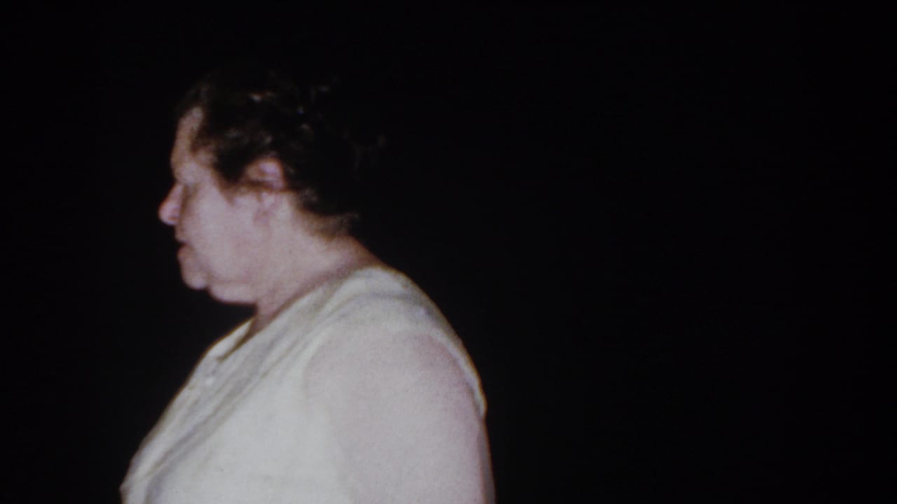 Adult woman in a white blouse shown in profile against a dark background.