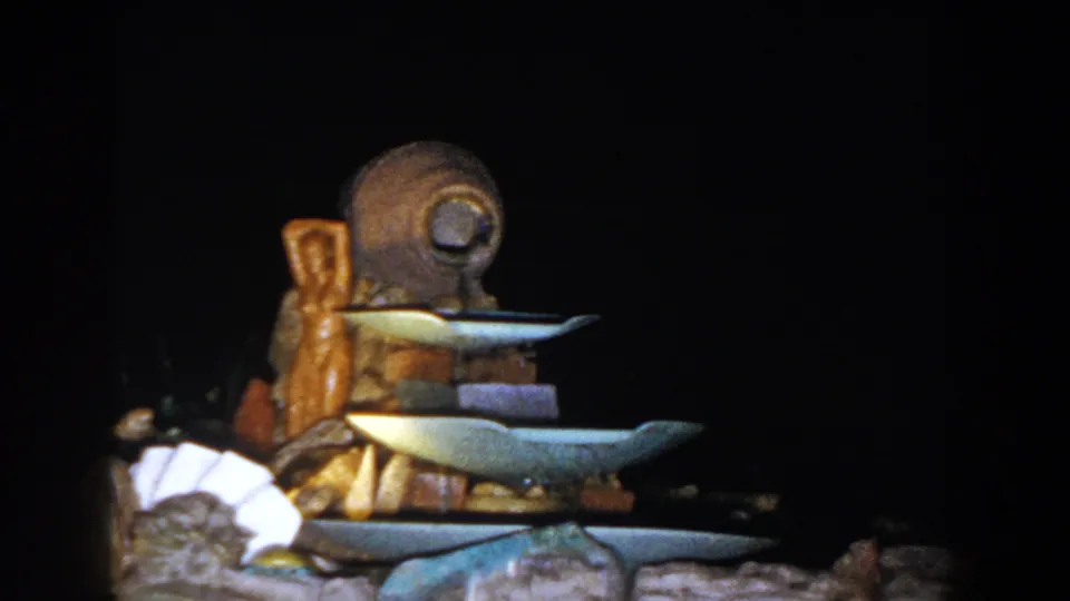 A slightly shifted 1960 home-movie view shows the same tiered fountain, with the stone base and dark garden setting visible.