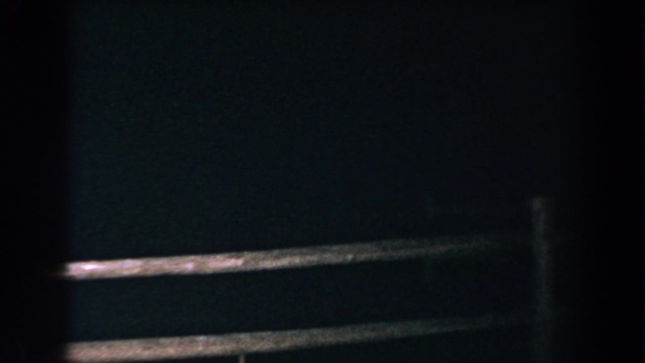 Dark nighttime view of a wooden rail fence with vertical posts.