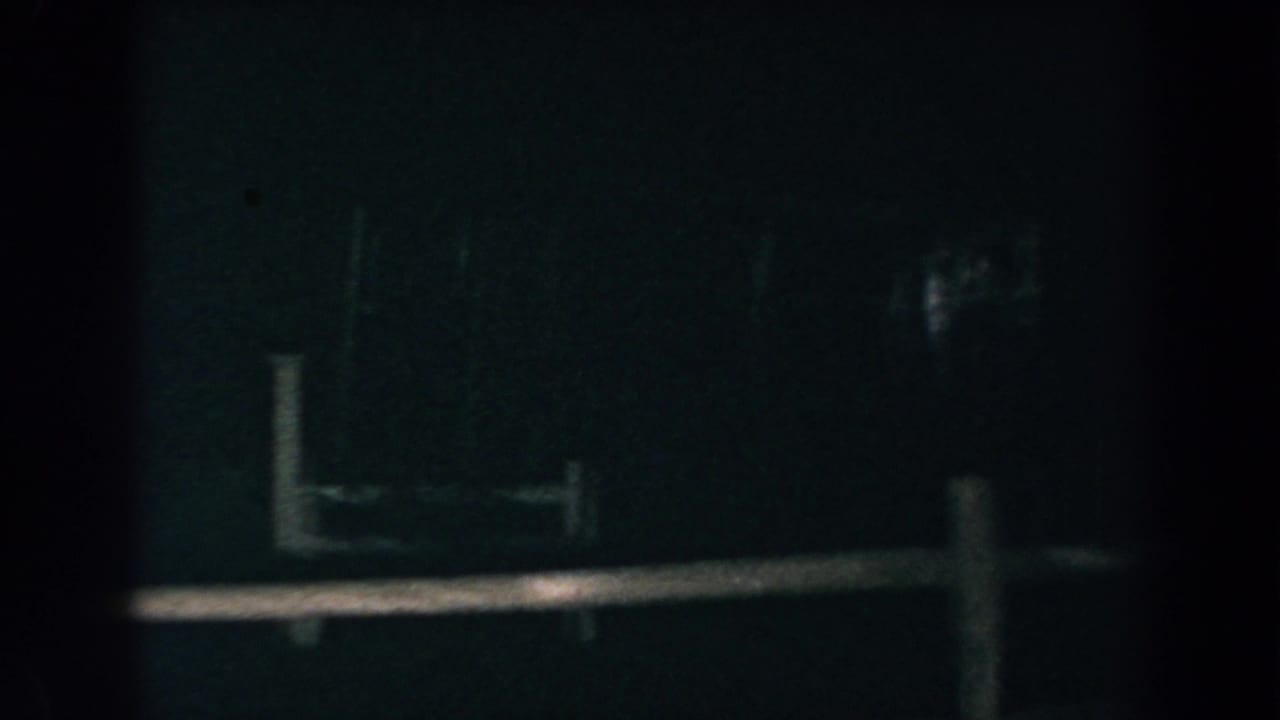 Dim fence rails and posts with faint light in the darkness.