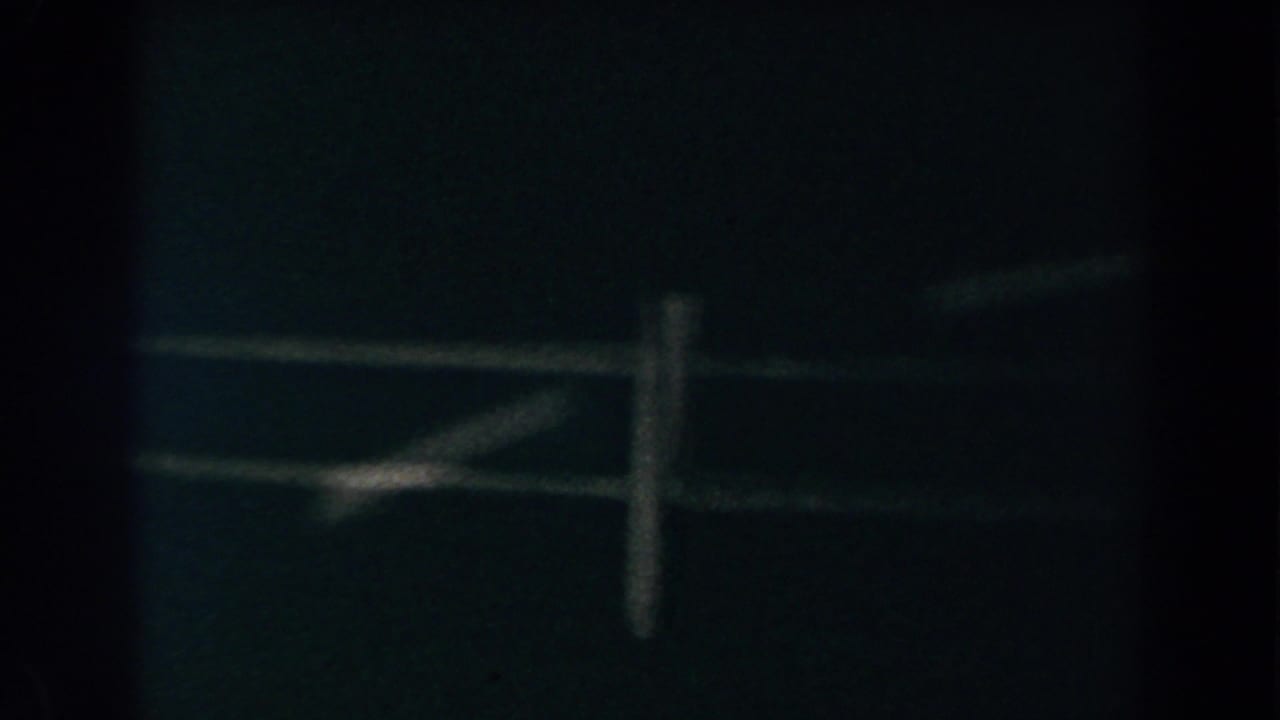 1960 Brighton, Michigan frame with soft, low-light view of fence rails and a vertical post in darkness.