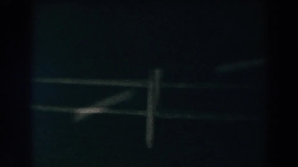 1960 Brighton, Michigan frame with soft, low-light view of fence rails and a vertical post in darkness.