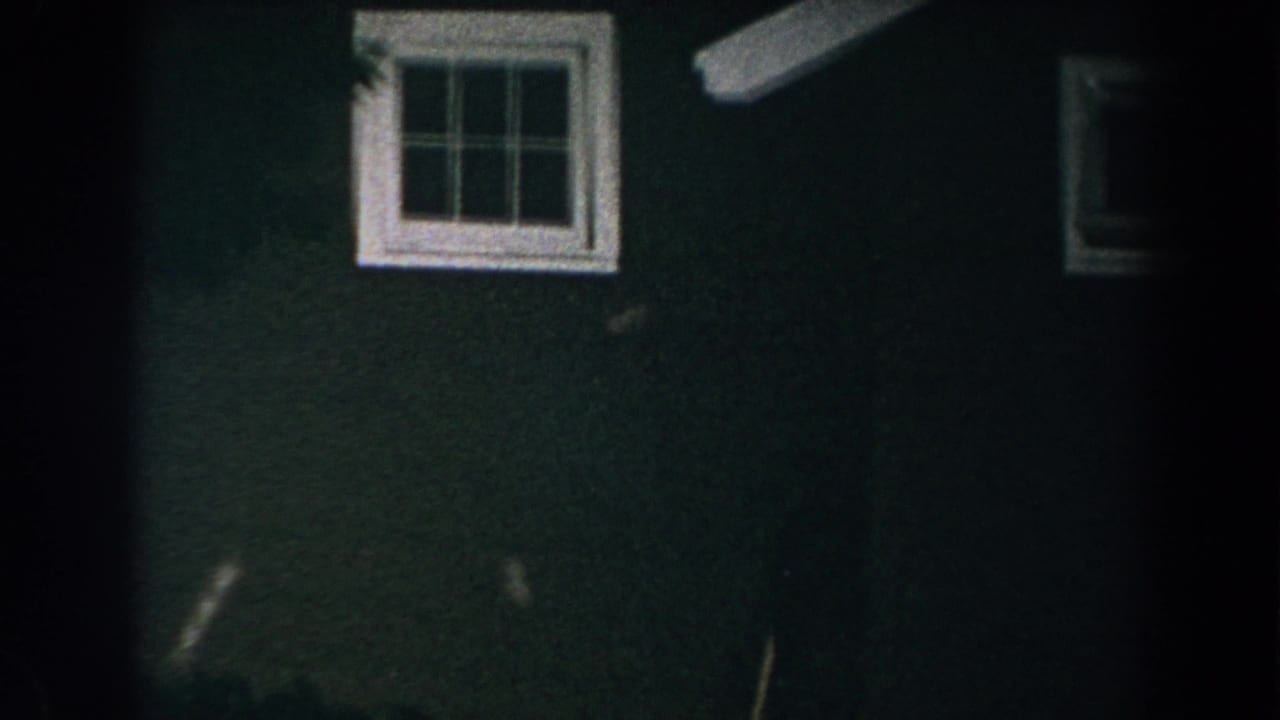 1960 Brighton, Michigan 8mm frame showing a dark green house exterior and white-trimmed window at night.