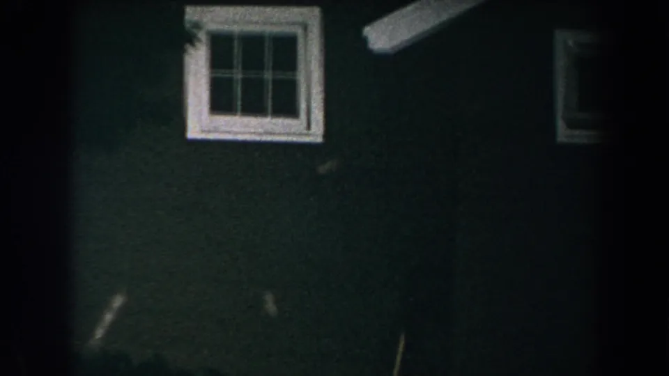 1960 Brighton, Michigan 8mm frame showing a dark green house exterior and white-trimmed window at night.