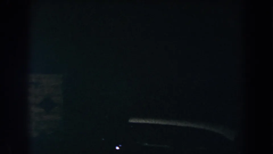 1960 Brighton, Michigan 8mm frame showing a barely visible car-like silhouette in deep nighttime shadow.