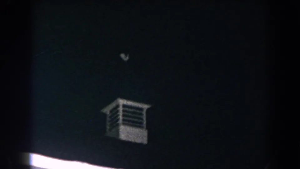 1960 Brighton, Michigan 8mm frame with a small white louvered tower over a mostly dark roofline and sky.