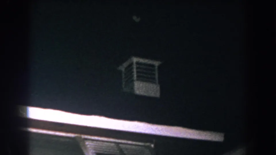 1960 Brighton, Michigan 8mm frame showing bright roof trim, a louvered tower, and a dark sky during the storm scene.