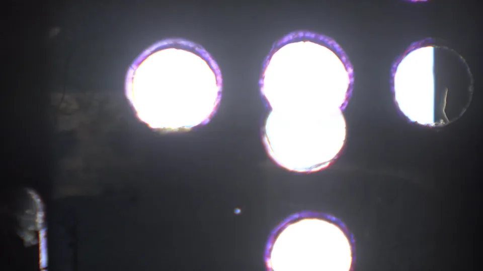 8mm frame with bright circular overexposures, dark surrounding film, and edge artifacts during the short exterior clip.