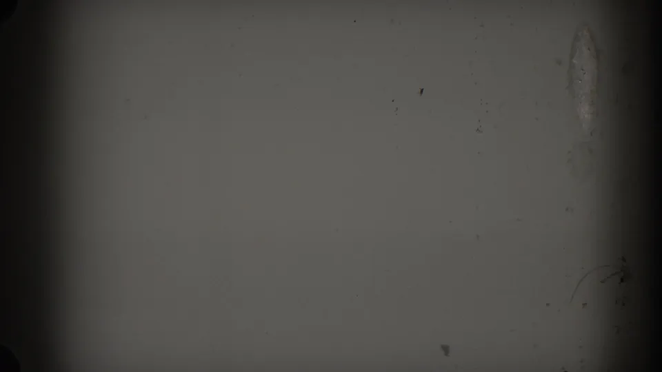 Mostly blank 8mm frame with gray exposure, dark vertical edge, dust specks, and a faint surface mark near the right side.