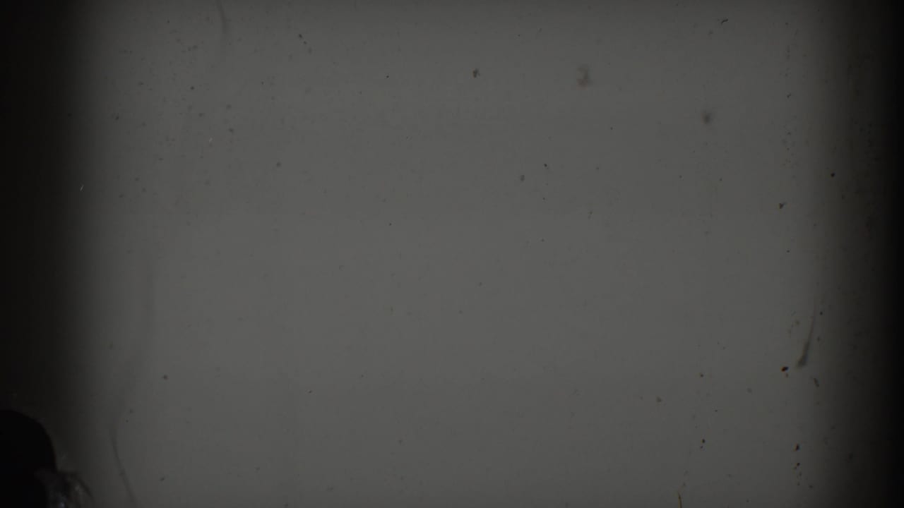 Dim gray film frame with vertical dark bands, dust, scratches, and faint exposure variation.