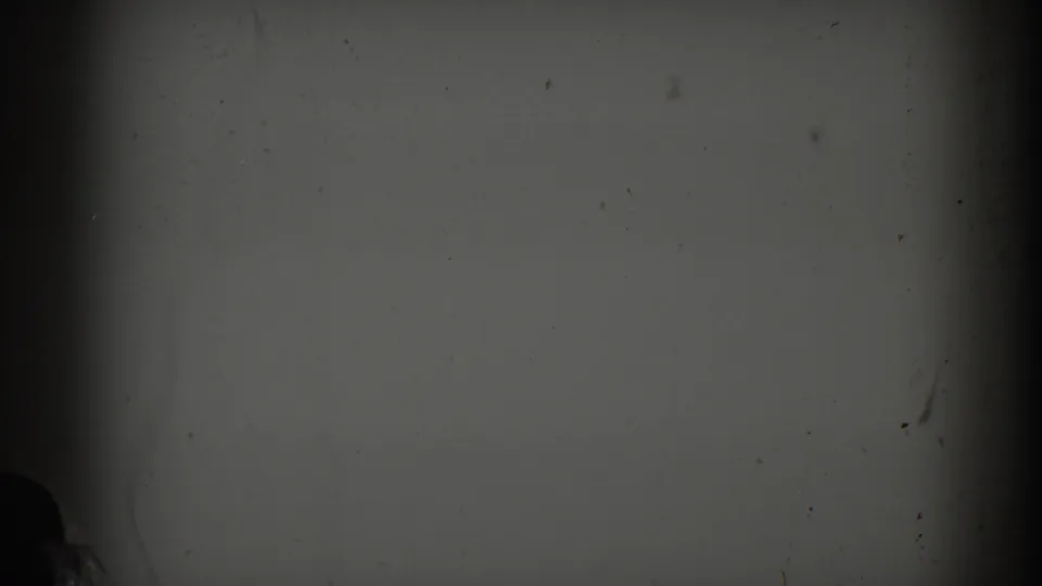 Dim damaged 8mm frame with gray exposure, vertical gate shadows, dust, and scratches; no identifiable people or objects are visible.