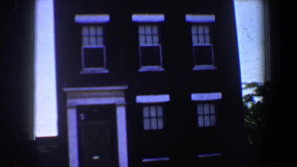1964 Saint Louis 8mm frame near the end of the pan, showing the three-story residence, repeated windows, entry steps, and right-side foliage.