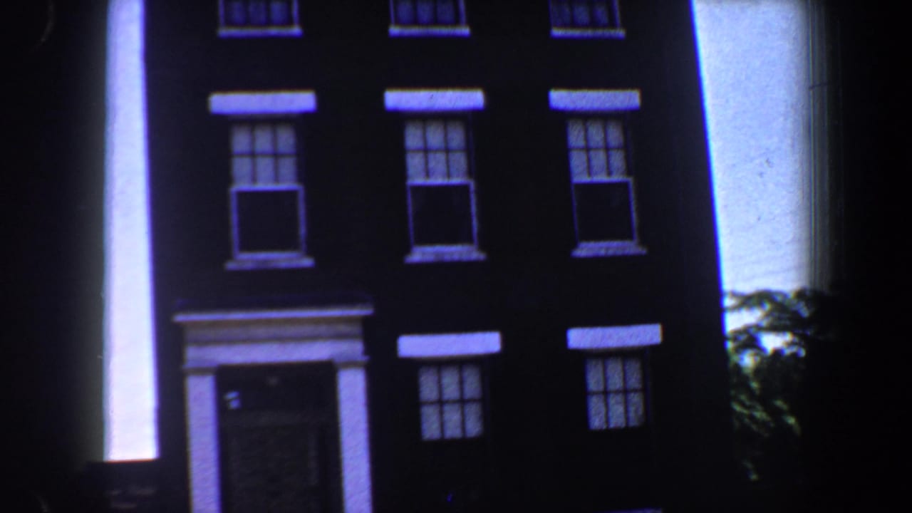 Dark brick building facade with white-trimmed windows and a columned entrance.