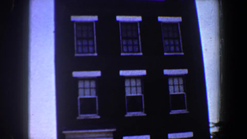 The 8mm frame holds on the Saint Louis building facade, showing stacked windows, white lintel-like trim, and part of the entrance.