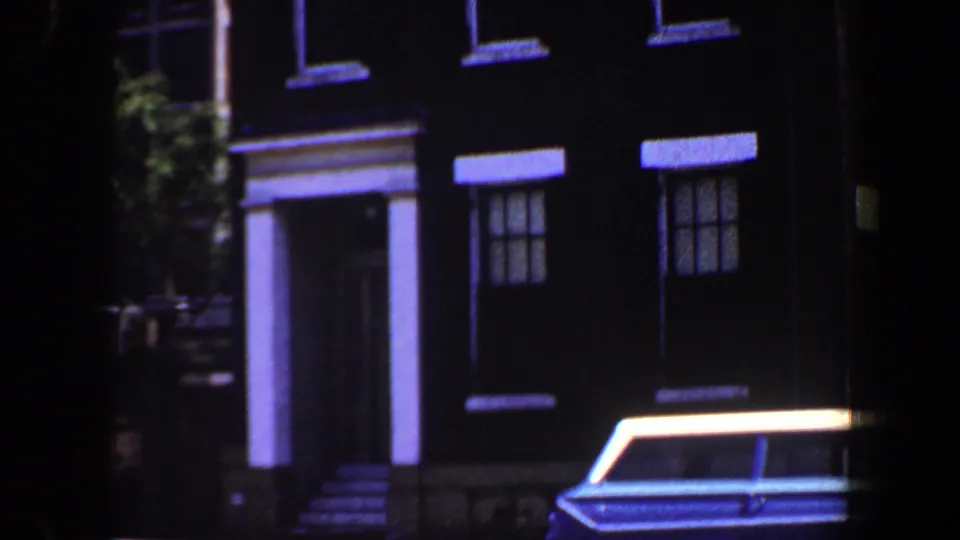 1964 Saint Louis street view with a columned brick building entrance and a blue-and-white station wagon parked in front.
