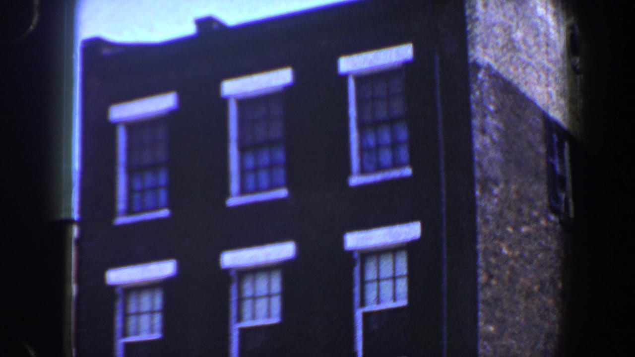 Upper brick facade with white window trim and blue sky above.