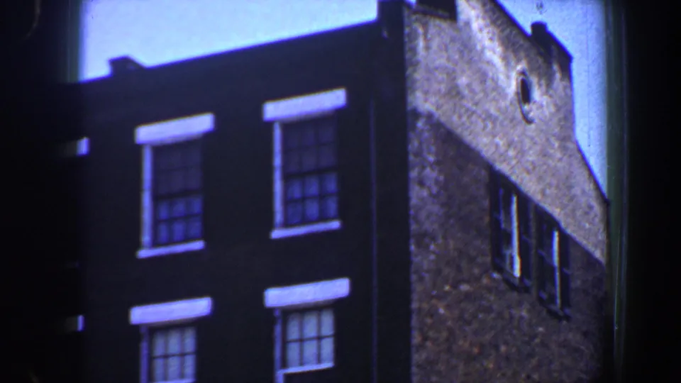 1964 Saint Louis 8mm view of double-hung windows on a dark brick wall next to a textured side wall.