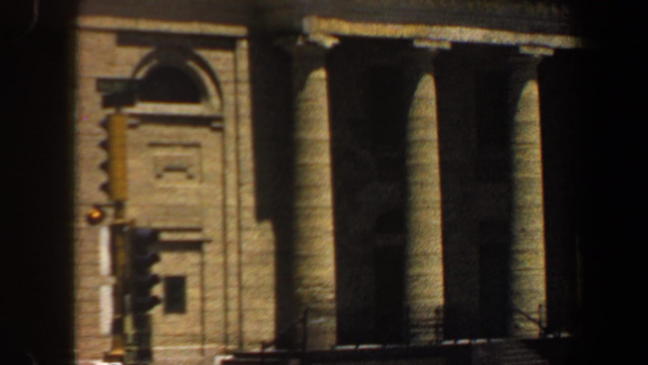 1964 Saint Louis 8mm frame showing a sunlit tan building facade with classical columns and an arched architectural detail.