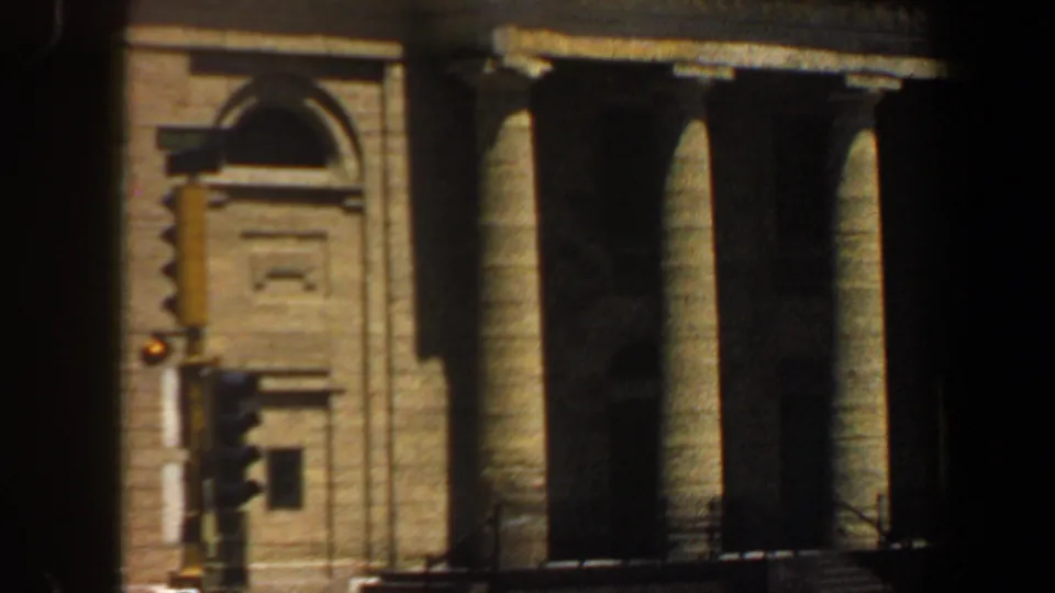 1964 Saint Louis 8mm frame showing a sunlit tan building facade with classical columns and an arched architectural detail.