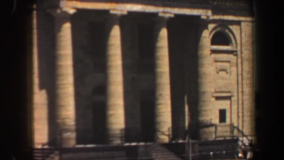 Visitor-shot 1964 Saint Louis view of a columned tan building facade, partly blocked by dark foreground framing.