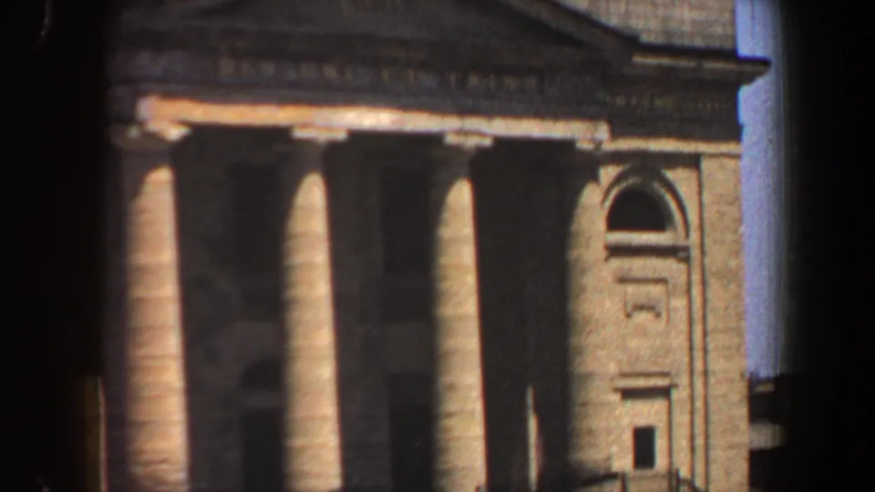 1964 Saint Louis 8mm frame with a closer crop of the columned tan facade and arched architectural feature.
