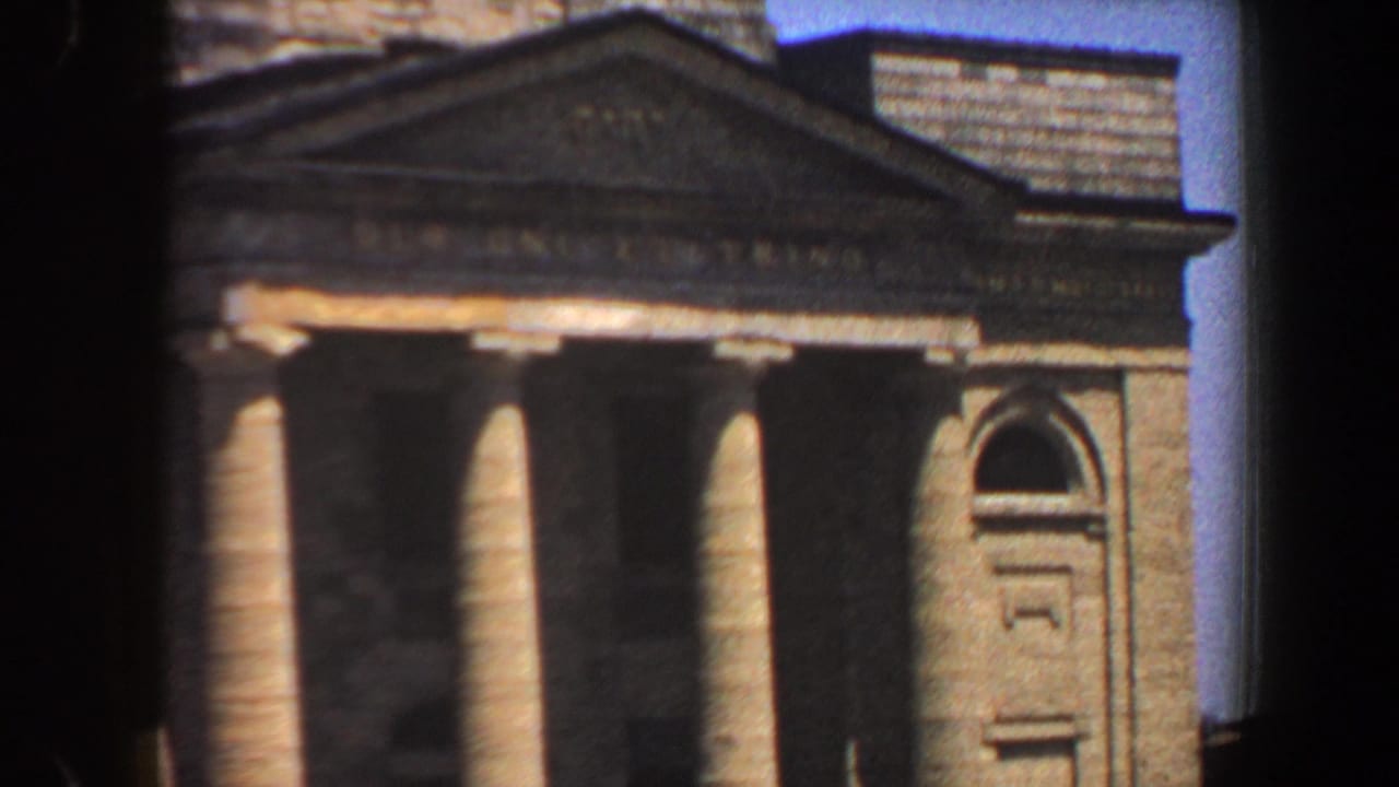 1964 8mm view of a St. Louis civic building facade with tall columns, pediment, masonry, and blue sky.