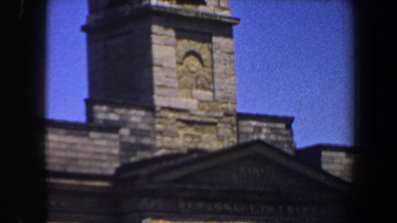 Stone church tower and pediment seen through dark 8mm frame borders.