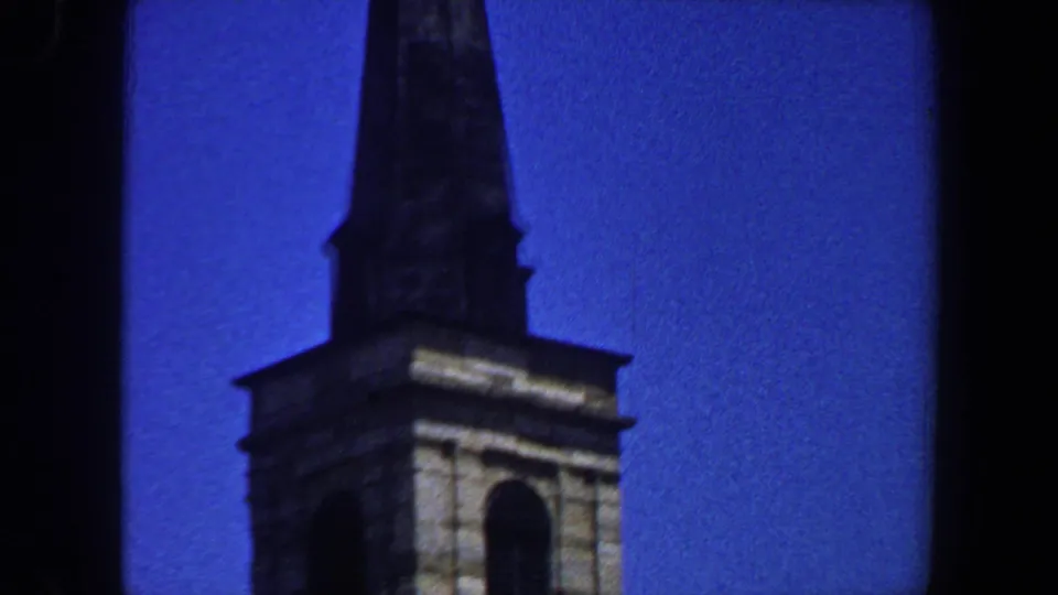Pointed steeple and arched tower window of a Saint Louis church, captured on 8mm film in 1964.
