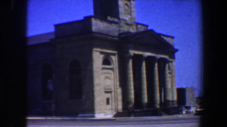 Saint Louis church exterior in 1964 home-movie footage, showing stone facade, columns, arched windows, and steeple.