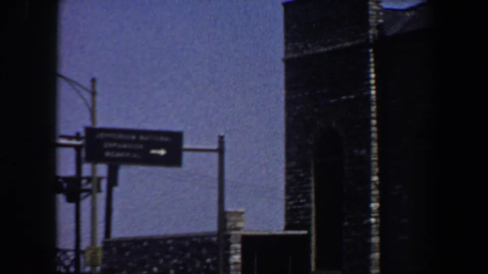 Saint Louis street signage and a tall masonry structure appear in a blue-shifted 1964 8mm frame.