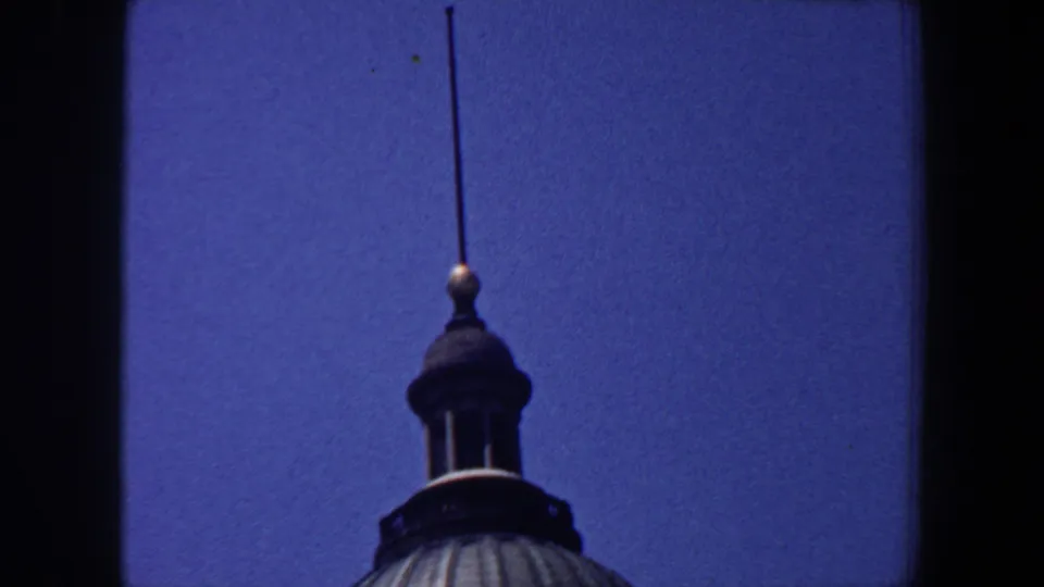 1964 Saint Louis 8mm frame showing a domed roof, cupola, and spire from a visitor-shot upward angle.