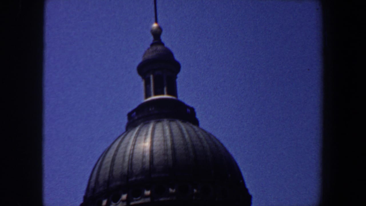 Upper portion of a ribbed dome with lantern against a blue sky.