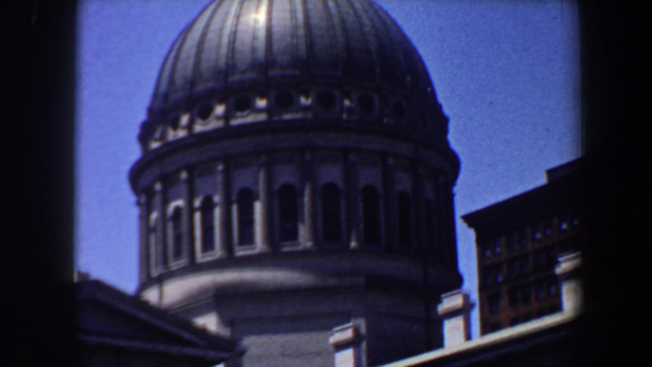 Domed historic building with arched windows and adjacent urban structures.