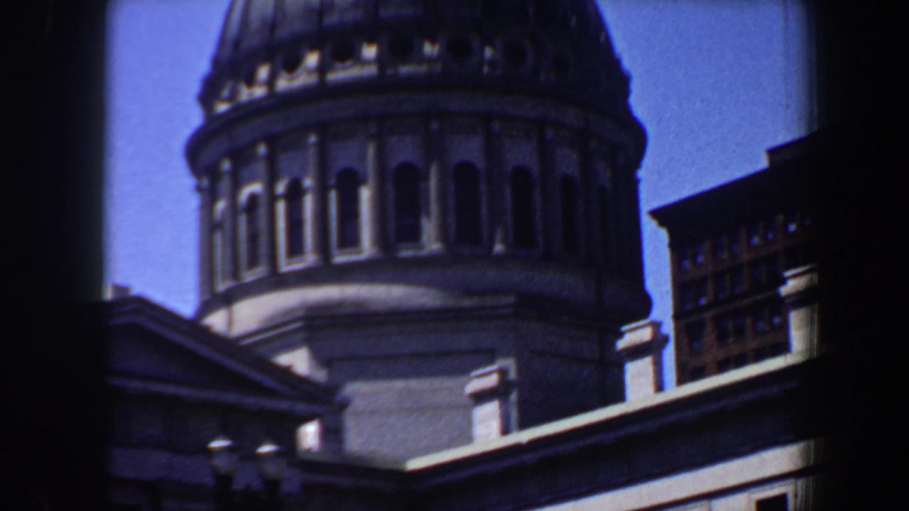 Close view of a large dome above a stone facade and nearby buildings.